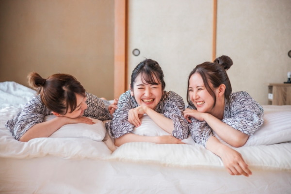 女子旅でベッドの上で笑い合う3人