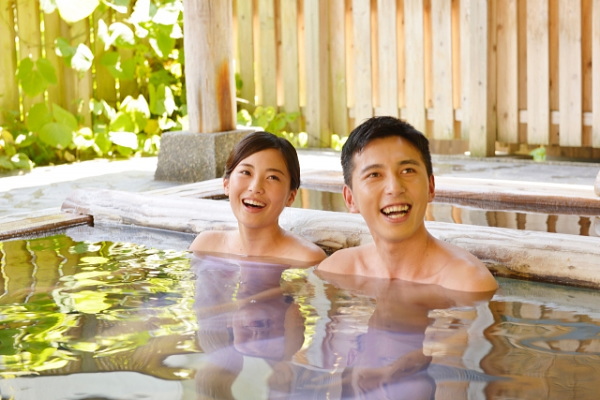 客室露天風呂で温泉を楽しむカップルのイメージ